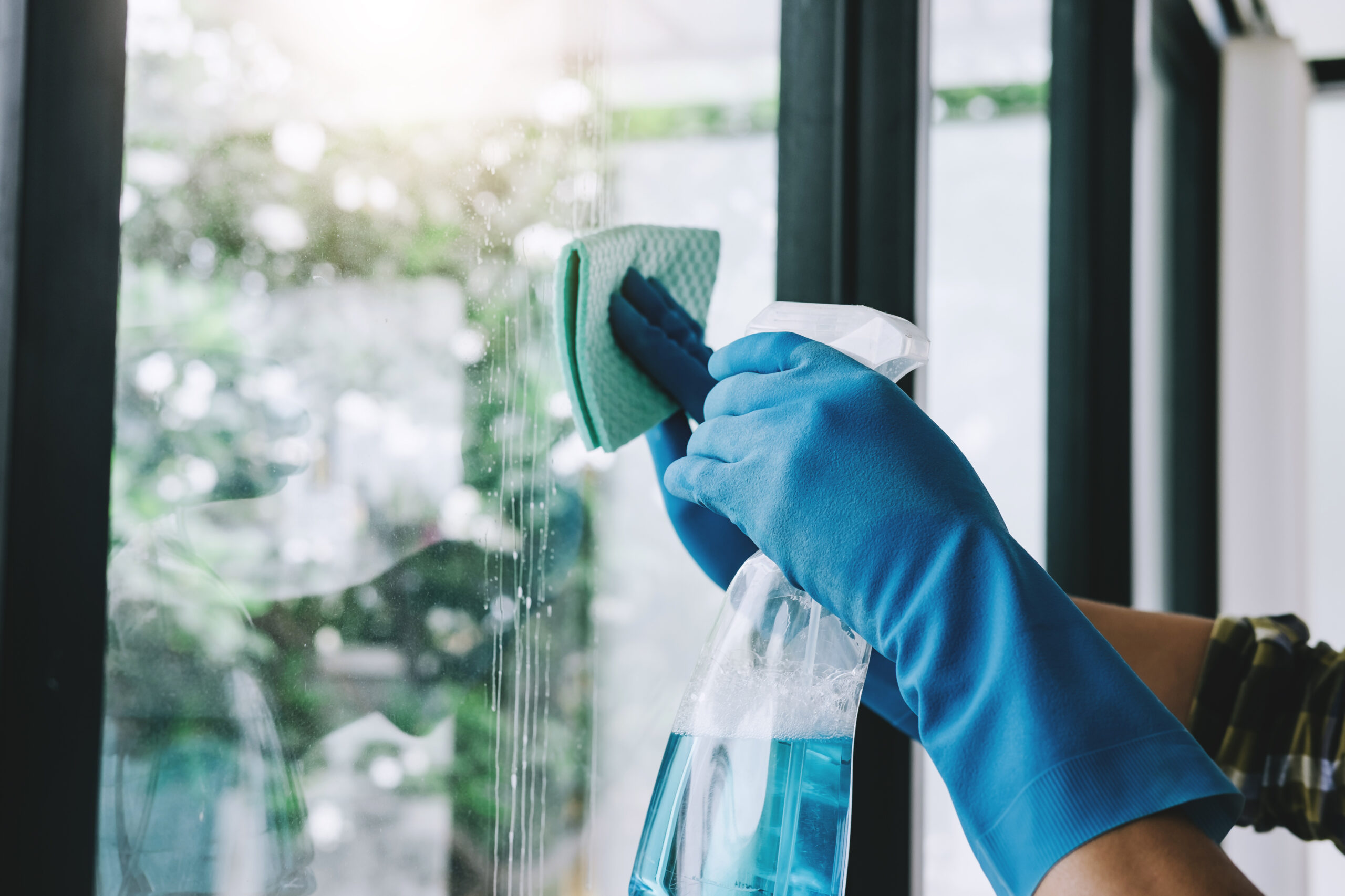 Husband housekeeping and cleaning concept, Happy young man wiping dust using a spray and a duster while cleaning in glass at home.